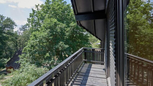 A balcony with a wooden floor and metal railing, overlooking a dense green forest. - Am Sternberg 38 by Interhome (Frankenau)