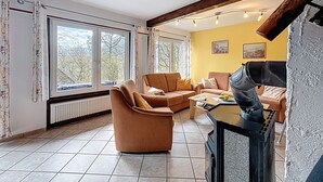 A living room with a fireplace, large windows, and a yellow wall. - Am Sternberg 38 by Interhome (Frankenau)
