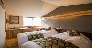 Two large beds with matching bedding, a desk, and a large mirror create a comfortable living and sleeping space.