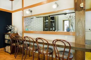 A dining area with wooden chairs and a large mirror reflecting the room. - Imi Ola House (Yufu)