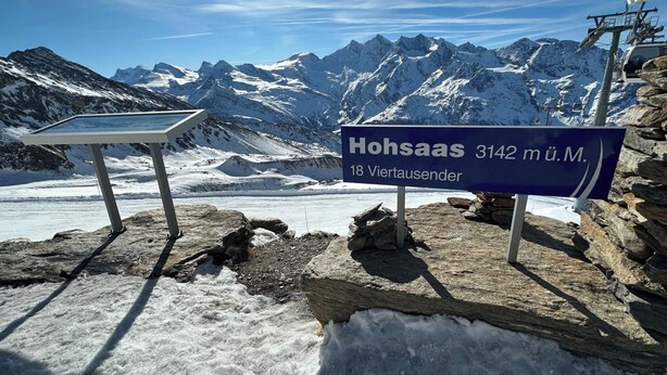 Bord dat de locatie 'Hohsaas 3142 m ü.M.' aangeeft, met uitzicht op besneeuwde bergen en een gletsjer.