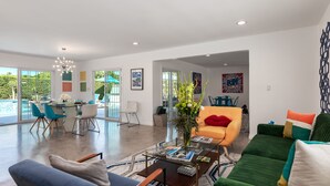 A spacious living area with a sofa, armchairs, a coffee table, and a dining area with chairs and a table.