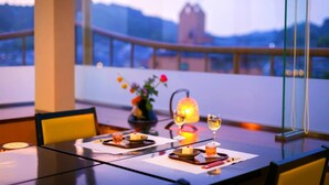 A dining table set with glasses of wine, a candle, and a vase with flowers. - Dogo Grand Hotel (Matsuyama)
