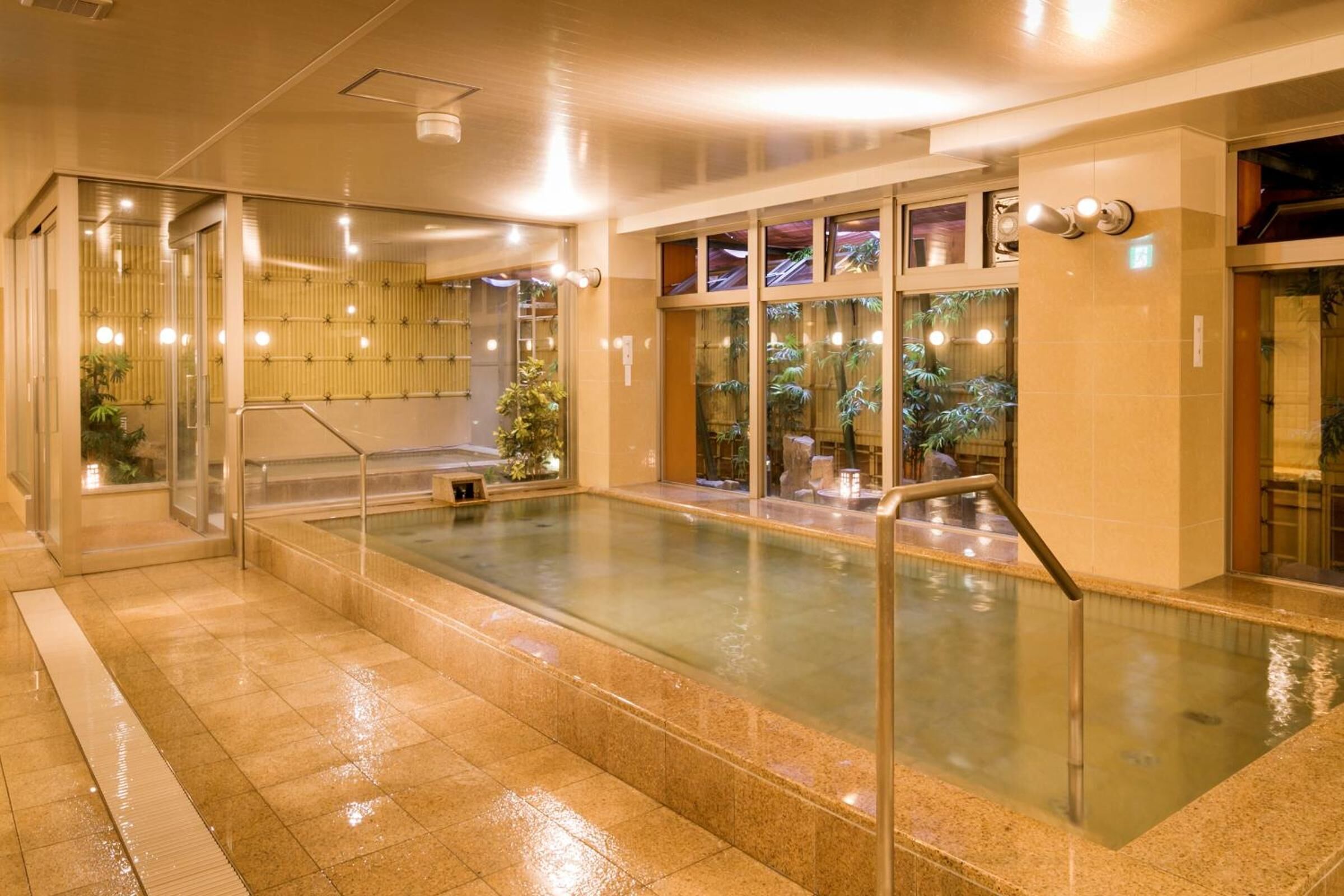A swimming pool with glass railings, a tiled floor, and a bamboo wall.