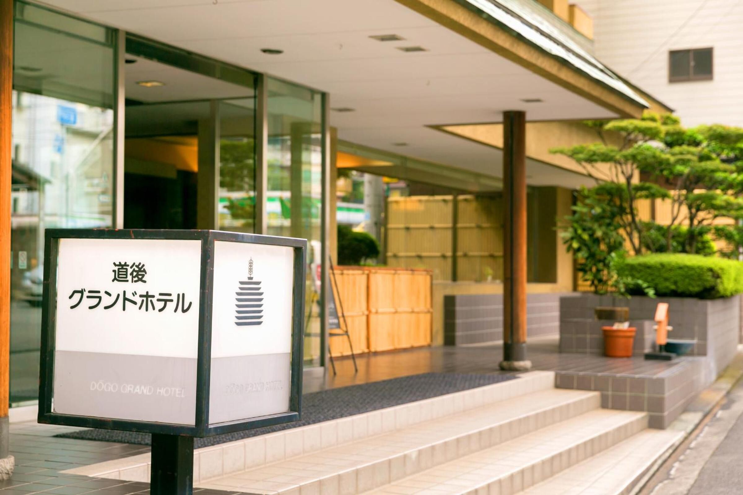 A hotel entrance with a signboard displaying the name in both Japanese and English.