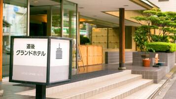 A hotel entrance with a signboard displaying the name in both Japanese and English.