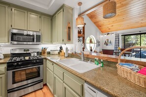 A modern kitchen with stainless steel appliances, a granite countertop, and a view of the outdoors.