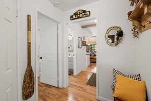 A hallway with a wooden spoon decoration, a sign for 'JUNE'S Lakehouse,' and a mirror with a bear design.
