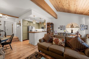 A modern living room with a sofa, a dining area, and a kitchen. - Junipine Lakefront Condo - Boulder Bay | Pool + Tennis | Walk to Lake (Big Bear Lake)