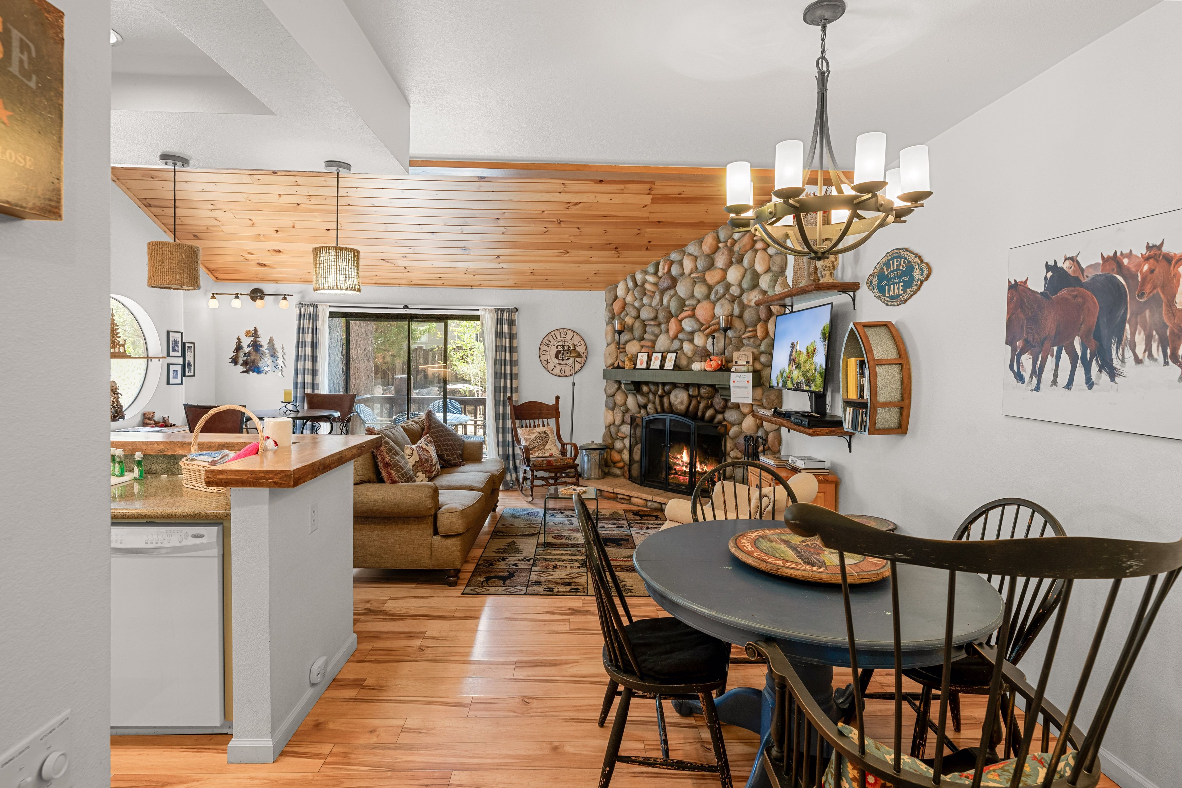 Un vaste espace de vie doté d’une cheminée, de parquets en bois et d’une table à manger avec des chaises.