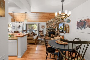 A spacious living area with a fireplace, wooden flooring, and a dining table with chairs.