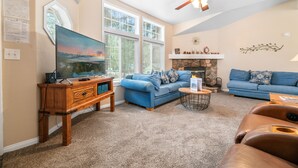 A living room with a large TV, two sofas, a fireplace, and a ceiling fan. - Wine Down - Fireplace, Fenced Yard, Deck, Barbecue (Big Bear City)