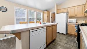A kitchen with a dishwasher, refrigerator, microwave, and wooden cabinets. - Wine Down - Fireplace, Fenced Yard, Deck, Barbecue (Big Bear City)
