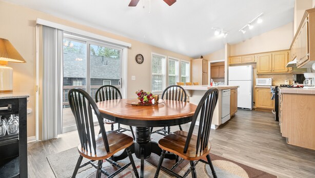A modern kitchen with a central island, wooden cabinets, and a dining area with a round table and chairs. - Wine Down - Fireplace, Fenced Yard, Deck, Barbecue (Big Bear City)
