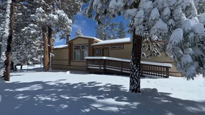 A snow-covered building with a wooden deck and snow-laden trees. - Wine Down - Fireplace, Fenced Yard, Deck, Barbecue (Big Bear City)