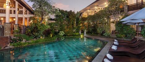 A pool with lounge chairs and a garden area.