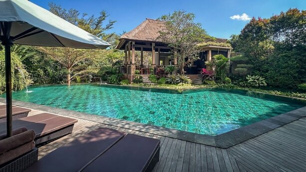 A clear blue pool with lounge chairs and a wooden deck. - The Mudru Resort by GenuineHost (Sukawati)