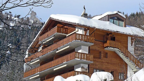 A multi-story wooden chalet with balconies, set against a snowy mountainous backdrop. - Dent Favre A 5 by Interhome (Ovronnaz)