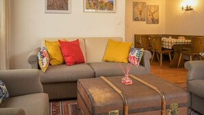 A cozy living room with a sofa, colorful cushions, a vintage suitcase, and a dining area with a table and chairs. - Dent Favre A 5 by Interhome (Ovronnaz)