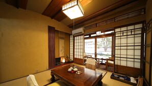 Een traditionele Japanse kamer met tatami vloerbedekking, een lage houten tafel met theeservies, verschuifbare shoji deuren en uitzicht op het omliggende landschap.