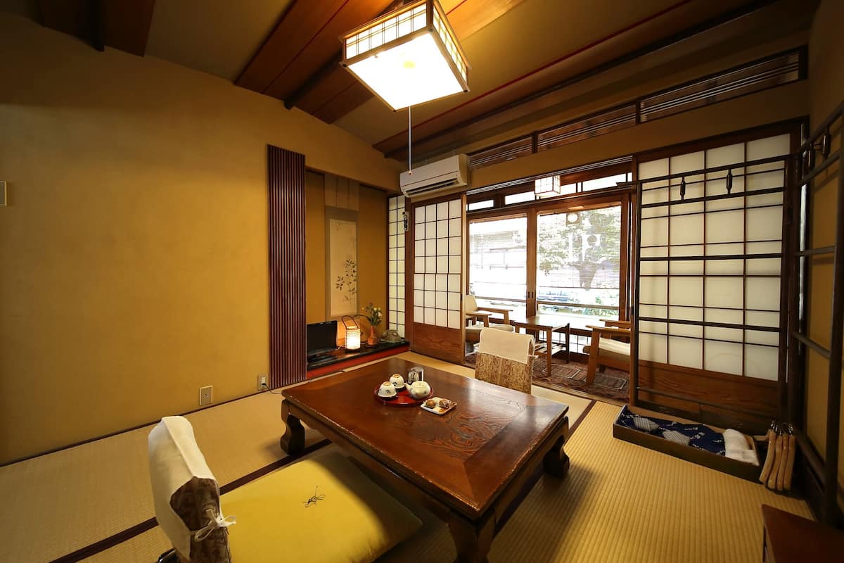 Een traditionele Japanse kamer met tatami vloerbedekking, een lage houten tafel met theeservies, verschuifbare shoji deuren en uitzicht op het omliggende landschap.