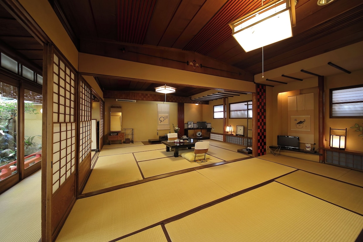 Una habitación japonesa tradicional con suelo de tatami, una mesa baja con cojín y puertas correderas.