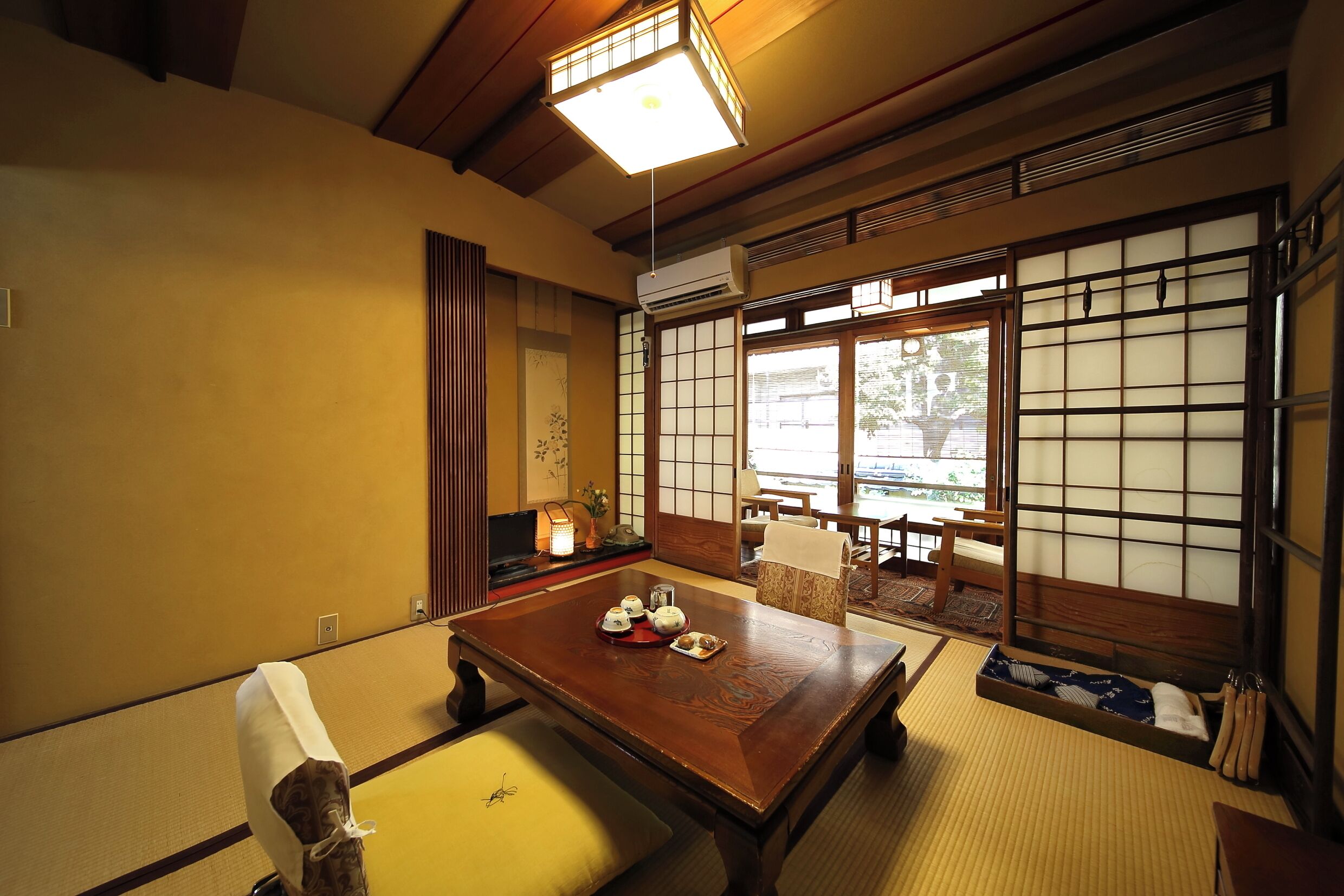 Une pièce de style japonais traditionnel, avec un sol recouvert de tatamis, une petite table en bois, des paravents shoji et une vue sur l’extérieur.
