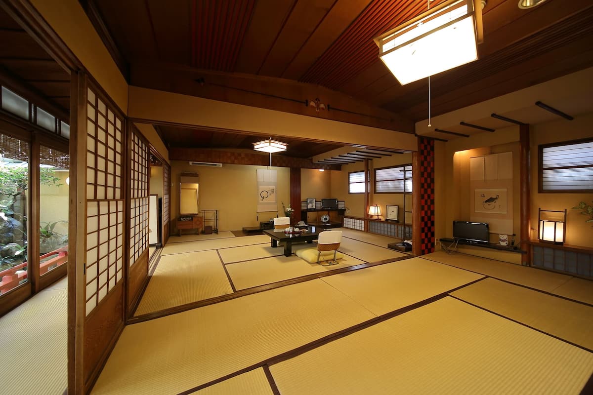 Een traditionele Japanse kamer met tatami vloerbedekking, een lage tafel met kussen, en schuifdeuren.