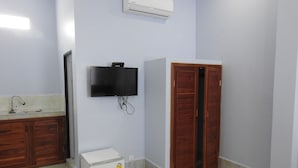 A bathroom with a sink, mirror, white cabinet, and a television mounted on the wall.