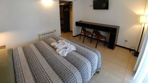 A bedroom with a bed, a desk, a chair, a TV, and a ceiling fan. - Posada Mia Nonna (Villa General Belgrano)