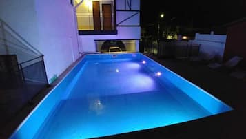 Una piscina al aire libre, sombrillas, sillones reclinables de piscina