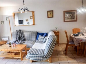 A cozy living room with a checkered sofa, wooden coffee table, and a dining area with a table set for two.