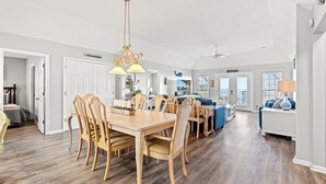 Ein geräumiger Essbereich mit Holztisch und Stühlen, einer Chandelierleuchtre und Blick zum Wohnzimmer.
