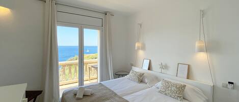 Une chambre avec un grand lit, une vue sur la mer et un balcon.
