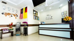 A hotel reception area with a modern design, featuring a reception desk, a world map, clocks, and flags.