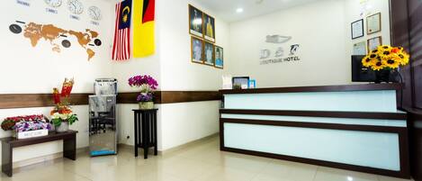 A hotel reception area with a modern design, featuring a reception desk, a world map, clocks, and flags.