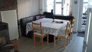 Un coin repas avec une table dressée pour quatre personnes, un canapé et un radiateur.