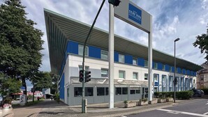 A modern hotel with a blue and white facade, a prominent sign for the Stay Inn, and a traffic light in the foreground. - Hotel Stay Inn Köln Leverkusen City (Leverkusen)