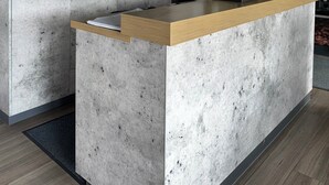 A reception desk with a wooden top and a concrete base, a clock, and a wall-mounted television. - Hotel Stay Inn Köln Leverkusen City (Leverkusen)