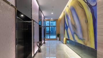 A modern interior with a glass wall, a marble floor, and a large abstract mural.