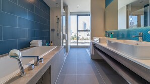 A modern bathroom with two sinks, a large bathtub, and a glass shower enclosure.