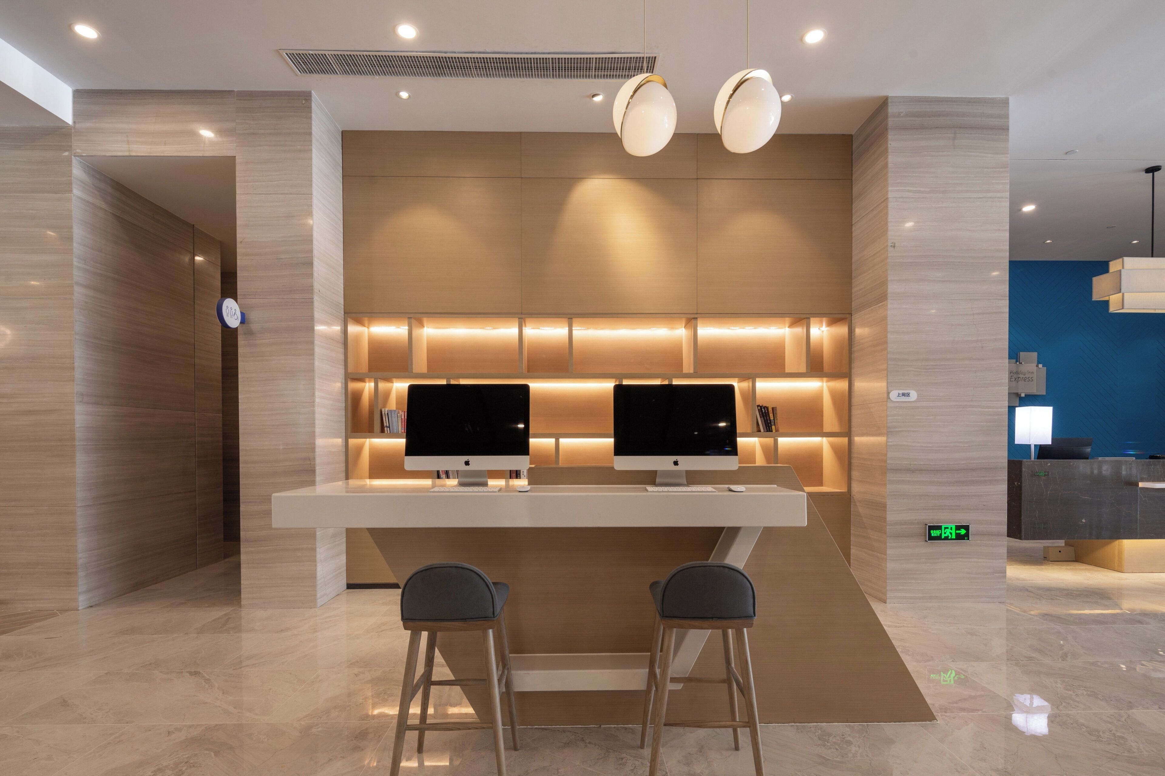 Un moderno vestíbulo de hotel con una recepción, dos monitores y una zona de estar.