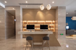 A modern hotel lobby with a reception desk, two monitors, and a seating area. - Holiday Inn Express Kaifeng City Center by IHG (Kaifeng)