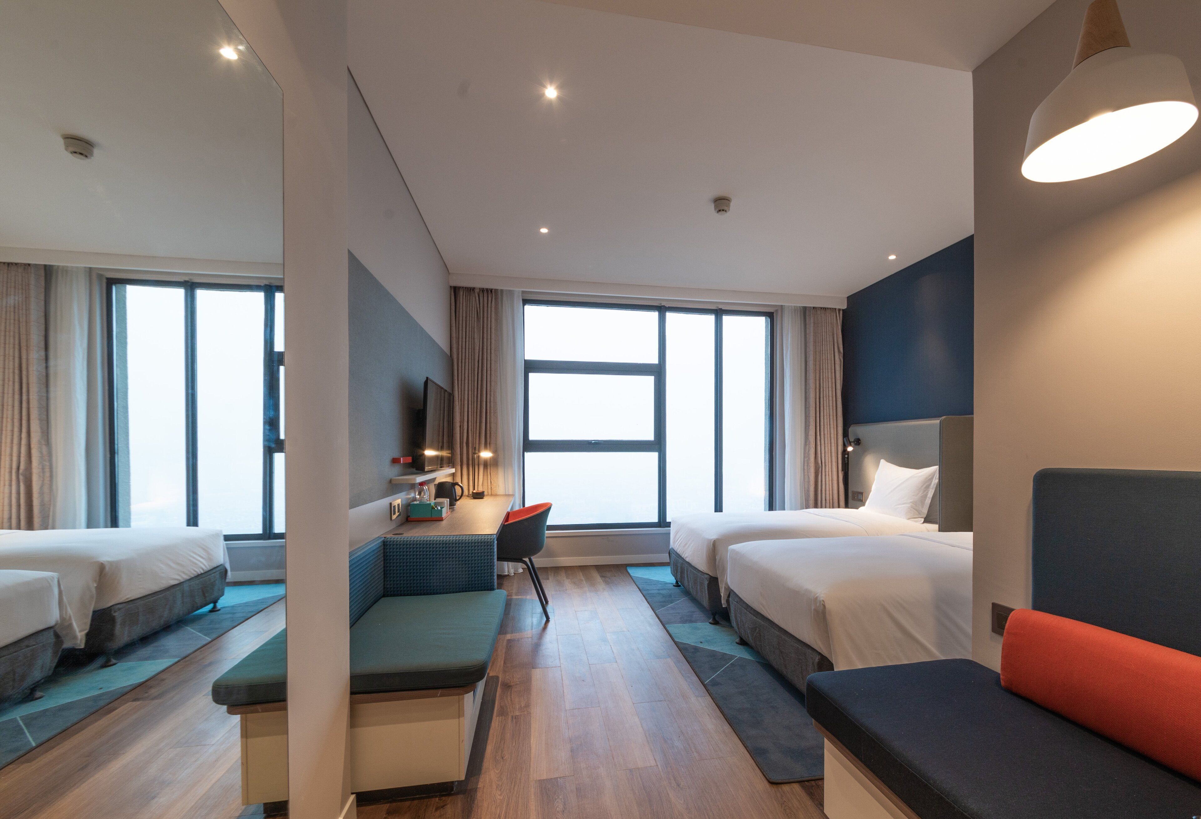 Een moderne hotelkamer met twee bedden, een bureau en een zithoek.
