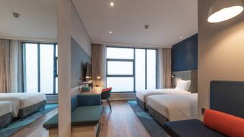 Een moderne hotelkamer met twee bedden, een bureau en een zithoek.
