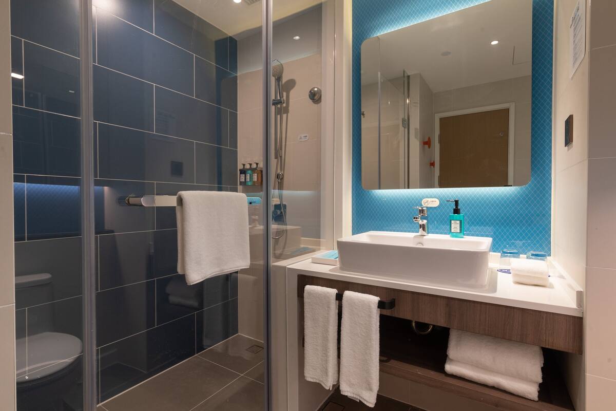 A modern bathroom with a glass shower enclosure, a white sink, and a large mirror.
