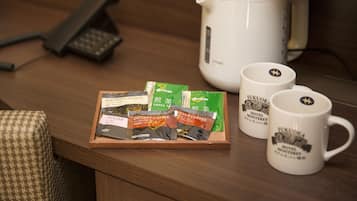 Un plateau en bois contenant des sachets de café instantané et deux tasses blanches ornées du logo de l’hôtel.