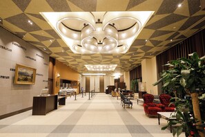 A hotel lobby with a check-in desk, seating area, and a large chandelier. - Hotel Monterey Fukuoka (Fukuoka)