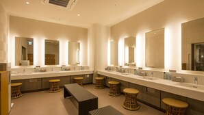 A modern bathroom with multiple sinks, large mirrors, wicker stools, and benches.