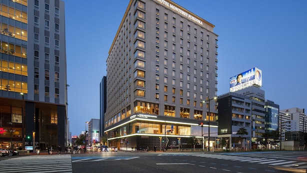 A modern hotel with a prominent entrance, multiple floors, and a large illuminated sign.